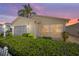 Charming home exterior featuring manicured hedges, screened garage, and inviting curb appeal at sunset at 1706 Moreno Pl, The Villages, FL 32159