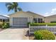 Exterior of a single-story home with a screened garage, well-kept landscaping, and a white picket fence at 1706 Moreno Pl, The Villages, FL 32159