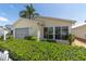 Cozy home featuring a screened garage, large windows, and lush landscaping at 1706 Moreno Pl, The Villages, FL 32159