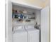 A functional laundry closet with a washer and dryer and shelving for storage at 1706 Moreno Pl, The Villages, FL 32159
