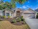Charming single-story home with a manicured lawn, two-car garage, and inviting front entrance with decorative door at 1741 Pennecamp Dr, The Villages, FL 32162