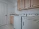 A laundry room with a washer, dryer, sink, and wooden cabinets at 1741 Pennecamp Dr, The Villages, FL 32162