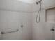 Close up of the tiled shower featuring a handheld shower head and a grab bar at 1741 Pennecamp Dr, The Villages, FL 32162