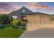 Inviting exterior view of a home with a spacious three-car garage and neatly manicured front lawn at dusk at 1796 Zientara Loop, The Villages, FL 32163