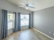 A relaxing bedroom with a ceiling fan, grey walls, wood-look flooring, and bright, natural light at 1954 Ladyfish Ave, The Villages, FL 32162