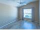 Cozy bedroom features neutral walls, wood-look flooring, natural light and ceiling fan with light at 1954 Ladyfish Ave, The Villages, FL 32162