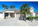 This exterior shot reveals meticulous landscaping, including white gravel accents, green shrubs and palm trees at 1954 Ladyfish Ave, The Villages, FL 32162