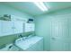 Well-organized laundry room with modern washer, dryer, and overhead storage cabinets at 1954 Ladyfish Ave, The Villages, FL 32162
