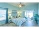 A bright main bedroom with a ceiling fan, light blue walls, light-colored wood floors, and backyard patio access at 1954 Ladyfish Ave, The Villages, FL 32162
