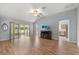 Bright living room featuring wood floors, vaulted ceilings, access to a screened lanai, and a glimpse of the kitchen at 2204 Margarita Dr, The Villages, FL 32159