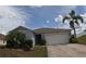 Charming single-story home featuring a two-car garage, palm trees, and a well-maintained front yard at 2256 Gladiolus Ln, Mascotte, FL 34753