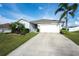 Inviting single-story home with a spacious driveway, manicured lawn, and lush tropical landscaping at 2256 Gladiolus Ln, Mascotte, FL 34753
