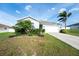 Well-maintained single-Gathering home featuring a two-car garage, green lawn, and tropical landscaping at 2256 Gladiolus Ln, Mascotte, FL 34753