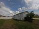 A view of the home's side yard, featuring healthy grass, a new fence, and a glimpse of the neighborhood at 2256 Gladiolus Ln, Mascotte, FL 34753