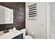 A well-lit bathroom with a dark wood accent wall, modern vanity, and striped shades at 2497 Heritage Green Ave, Davenport, FL 33837