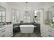 Bright bathroom featuring a soaking tub, white cabinets, and large windows with shutters at 2497 Heritage Green Ave, Davenport, FL 33837