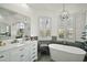 Bright bathroom featuring a soaking tub, white cabinets, and large mirrors at 2497 Heritage Green Ave, Davenport, FL 33837