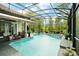 The pool includes a hot tub and a screened lanai, surrounded by lush greenery at 2497 Heritage Green Ave, Davenport, FL 33837