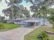 A front shot showcasing a single-story house, featuring a carport, flag, and verdant surroundings at 2529 Cr 448, Lake Panasoffkee, FL 33538
