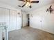 A cozy bedroom with plush carpet, a ceiling fan, a closet, and a doorway to another room at 26619 Bimini Dr, Tavares, FL 32778