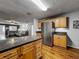 Open-concept kitchen with stainless steel refrigerator, wood cabinets, granite countertops, and wood flooring at 26619 Bimini Dr, Tavares, FL 32778