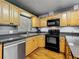 Kitchen featuring black appliances, wood cabinets, granite countertops, and wood flooring at 26619 Bimini Dr, Tavares, FL 32778