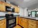 Eat-in kitchen featuring wood cabinets, granite countertops, and black appliances at 26619 Bimini Dr, Tavares, FL 32778