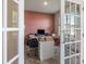 Stylish home office featuring a pink accent wall, desk, seating and french doors at 3235 Buoy Cir, Winter Garden, FL 34787