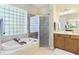 Bathroom featuring soaking tub, glass block window, and double sink vanity at 33222 Irongate Dr, Leesburg, FL 34788
