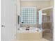 Bright bathroom with soaking tub, glass block window, and separate shower at 33222 Irongate Dr, Leesburg, FL 34788