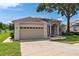 Charming home with a two-car garage, manicured lawn, mature landscaping, and attractive water feature at 33222 Irongate Dr, Leesburg, FL 34788