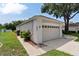 Garage and walkway with neatly maintained landscaping featuring shrubbery and rocks at 33222 Irongate Dr, Leesburg, FL 34788