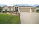 Charming home exterior with a well-manicured lawn, mature landscaping, and attached two-car garage at 3354 Truluck Pl, Oxford, FL 34484
