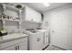 Well-organized laundry room with sink, upper cabinets, floating shelves, and washer and dryer at 3354 Truluck Pl, Oxford, FL 34484