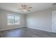 Light-filled bedroom featuring wood-look floors, a ceiling fan, a window with backyard views, and a crisp white door at 34107 Alameda Dr, Sorrento, FL 32776