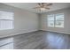 Bright bedroom featuring wood-look flooring, a ceiling fan, and large windows providing natural light and backyard views at 34107 Alameda Dr, Sorrento, FL 32776