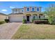 Charming two-story home featuring a brick driveway, attached garage, and inviting front porch with stone accents at 34107 Alameda Dr, Sorrento, FL 32776