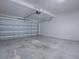 Spacious garage with an automatic door opener, exposed ceiling fixtures, and concrete flooring at 34107 Alameda Dr, Sorrento, FL 32776