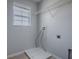 Functional laundry room with a window, gray walls, tile flooring, and a wire rack for storage and organization at 34107 Alameda Dr, Sorrento, FL 32776