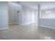 Open-concept living room features neutral tile flooring, grey walls, and views into dining room and entryway at 34107 Alameda Dr, Sorrento, FL 32776