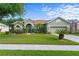 Landscaped front yard and exterior of a single-story home with stone accents and a two-car garage at 3440 Tumbling River Dr, Clermont, FL 34711