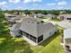 Beautiful aerial view of single-story home with a large screened lanai, gray roof, and lush green lawn at 3800 Woodleaf Ct, Leesburg, FL 34748