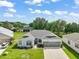 Aerial view of the gray roof home with a well-manicured lawn and a two car garage at 3800 Woodleaf Ct, Leesburg, FL 34748