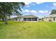 Backyard featuring a large manicured lawn and covered lanai area at 3800 Woodleaf Ct, Leesburg, FL 34748