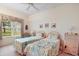 Bright bedroom featuring twin beds with floral comforters, dresser, and a large window with natural light at 3800 Woodleaf Ct, Leesburg, FL 34748