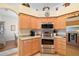Well-lit kitchen with stainless steel appliances, wooden cabinets, and an adjacent dining area at 3800 Woodleaf Ct, Leesburg, FL 34748