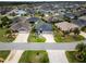 Aerial view showcases a gray home with a three-car garage, lush landscaping, and mature palm trees in a community at 3942 Zenith Loop, The Villages, FL 32163