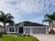 Charming single-story home with a three-car garage and well-manicured landscaping, framed by mature palm trees at 3942 Zenith Loop, The Villages, FL 32163