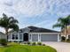 Attractive single-story house featuring a three-car garage, complemented by lush green lawns and swaying palm trees at 3942 Zenith Loop, The Villages, FL 32163