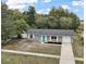 View of the single-story home with gray siding, white trim, manicured front yard, and inviting blue door at 425 Marion Oaks Dr, Ocala, FL 34473